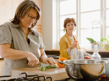 Foto von zwei Frauen beim Schneiden von Gemüse in einer Küche