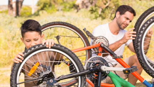 Foto von Sohn und Vater bei einer Fahrrad-Reparatur