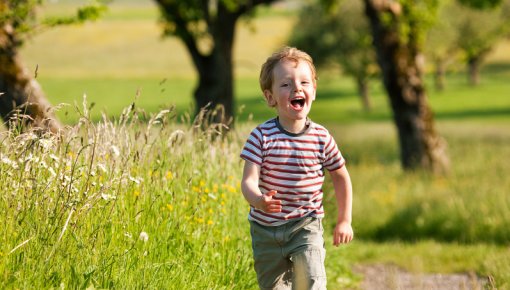 Foto von kleinem Jungen, der über eine Wiese läuft