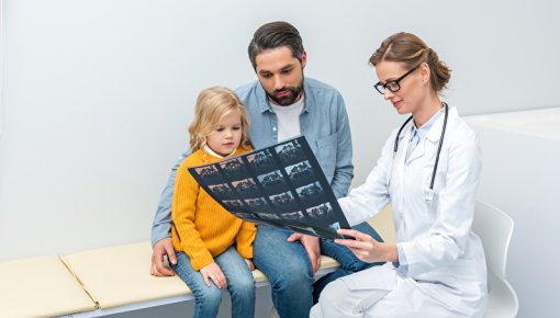 Foto von Vater und Tochter im Diagnose-Gespräch mit einer Ärztin