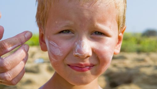 Foto von kleinem Jungen mit Sonnencreme