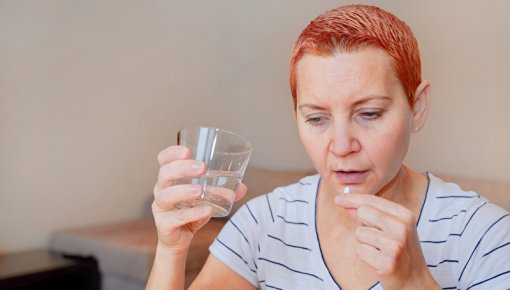 Foto von Frau bei Tabletteneinnahme mit Wasserglas
