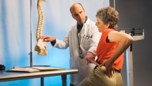 Foto von Orthopäde und Patientin mit Rückenschmerzen