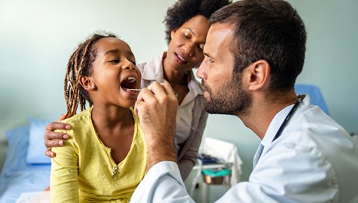 Foto von Arzt bei der Untersuchung einer kleinen Patientin