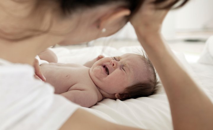 Foto von Mutter am Bett ihres schreienden Babys