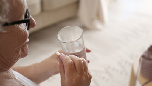 Ältere Dame mit Wasserglas bei der Einnahme einer Tablette