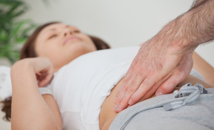 Foto von liegender Patientin, deren Bauch abgetastet wird