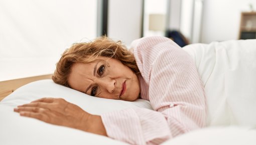 Foto von einer erschöpften Frau, die im Bett liegt 