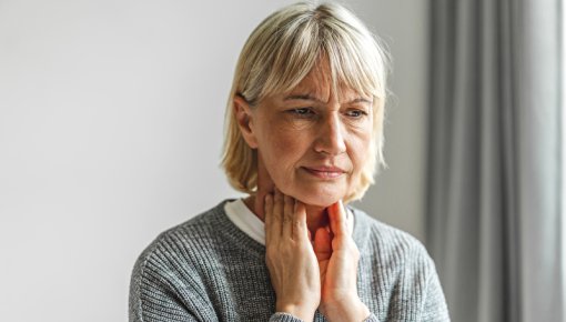 Foto von Frau, die ihren Hals abtastet