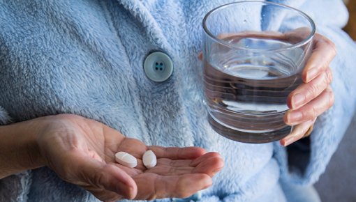 Seniorin mit Tabletten und Wasserglas