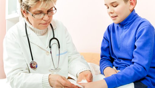 Foto von Ärztin bei der Versorgung von kleinem Jungen mit Schnittwunde am Finger