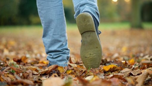 Foto von Füßen eines Mannes, der durch Herbstlaub geht