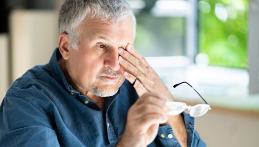 Foto von Mann mit Brille in der Hand, der sich das Auge reibt 