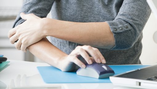 Foto von Frau mit schmerzendem Ellenbogen bei der Computerarbeit