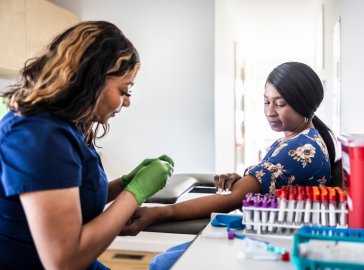 Foto von Patientin und Ärztin bei der Blutabnahme