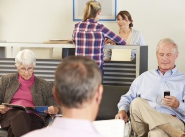 Gruppe von Patienten im Rezeptionsbereich einer Arztpraxis