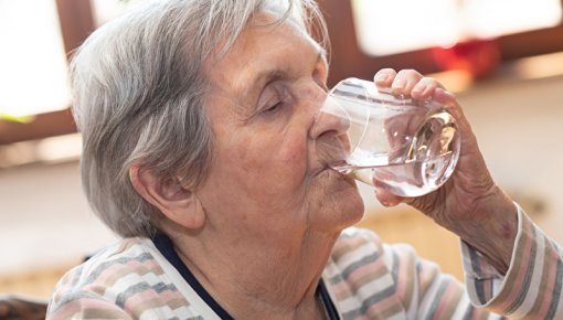 Foto einer Seniorin mit einem Glas Wasser