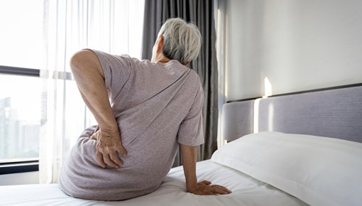 Foto von Frau mit Rückenschmerzen morgens beim Aufstehen