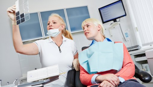 Foto von Zahnärztin und Patientin bei der Besprechung einer Röntgenaufnahme