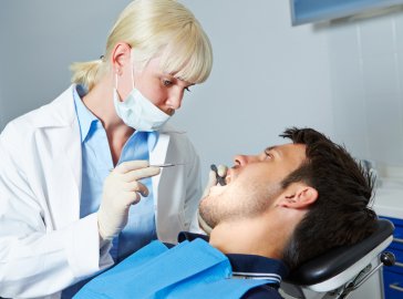 Foto von Zahnärztin und Patient im Behandlungsstuhl