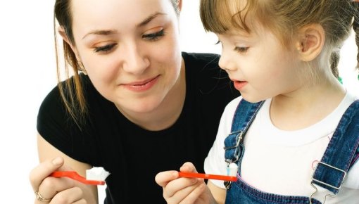 Foto von Mutter und kleiner Tochter beim Zähneputzen