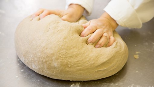 Foto von Händen, die ein Brot kneten