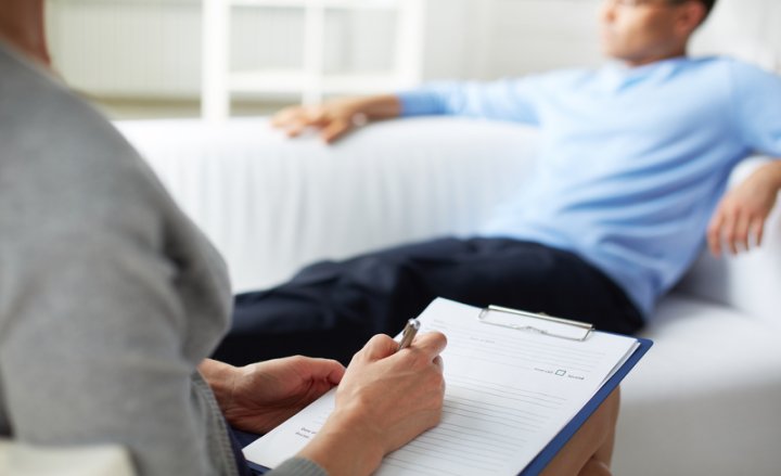 Foto von männlichem Patienten auf einer Couch und Therapeutin